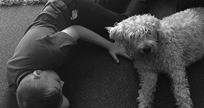 Child on classroom floor playing with a dog